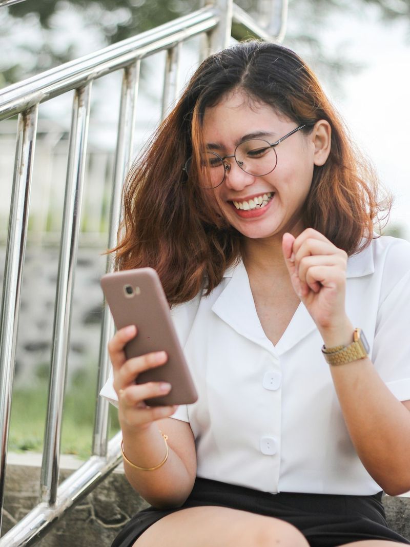 Mujer joven riéndose mientras mira su celular