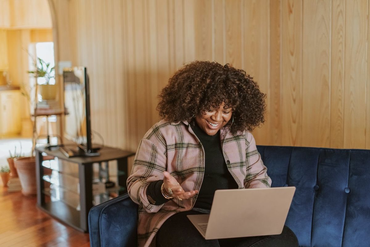 Mujer sonriendo con su laptop en el sofá